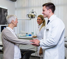 Senior woman meeting dentists and shaking hands