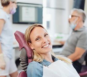 Blonde female patient sitting in dental chair and smiling