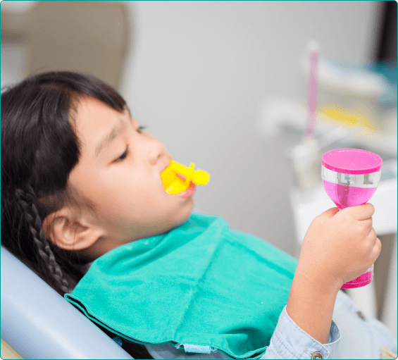 Young girl in dental chair with fluoride trays over her teeth