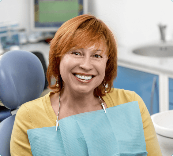 Smiling redheaded woman in dental chair