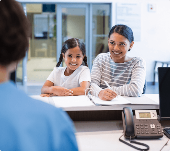 Woman with her daughter at dental office reception desk