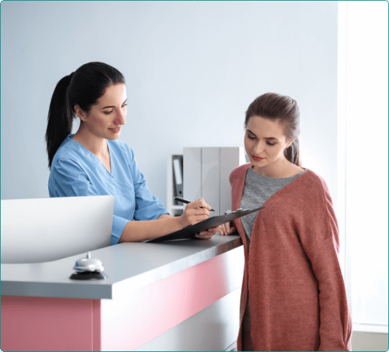 Dental team member showing a patient where to sign on a clipboard