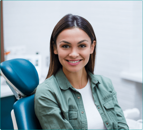 Woman in green jacket smiling in dental chair