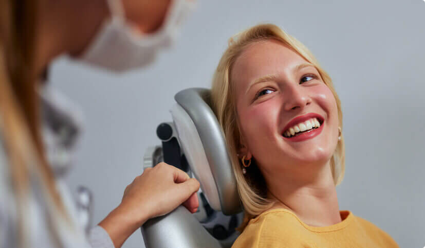 Woman in yellow sweater smiling at her dentist in Bangor