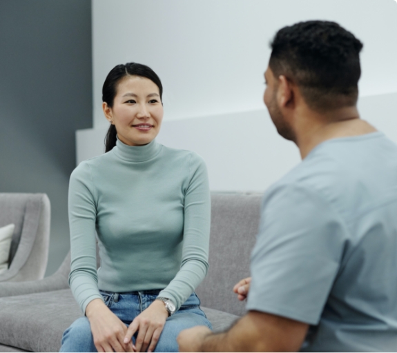 Woman talking to dental team member on couch