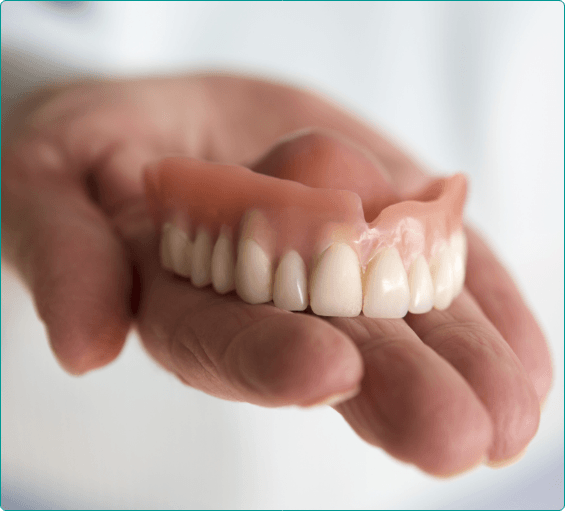 Dentist holding a full upper denture in their hand