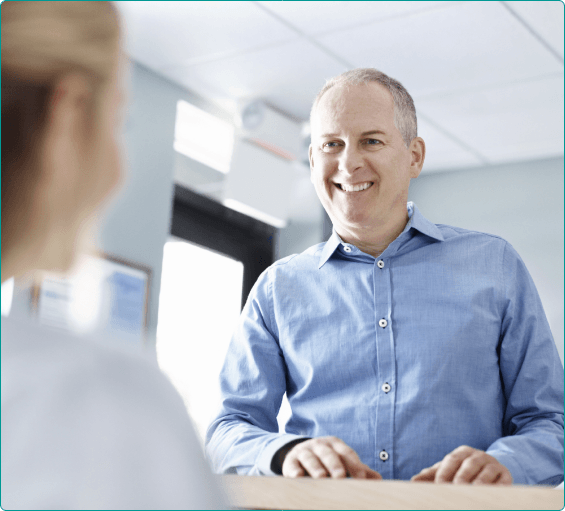 Man smiling at receptionist in Bangor dental office